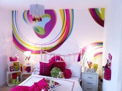 A girl's bedroom with a colorful mural on the wall featuring wallpaper from ohpopsi.com.