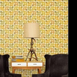 A yellow Orla Kiely wallpaper with black chairs and a lamp in front of it from the new collection.