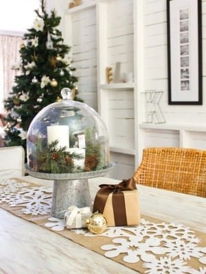 A festive dining table dressed for the Christmas season with a snow globe centerpiece.