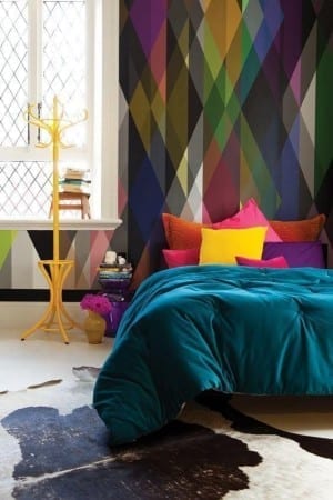 A colorful bedroom with circus wallpaper and a cowhide rug.