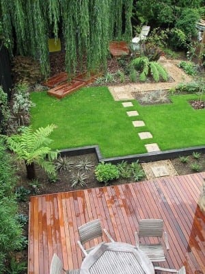 An aerial view of a garden with a refreshing wooden decking and a cozy wooden table.