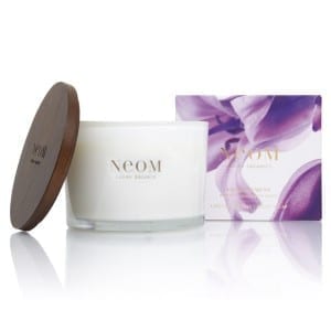 An Enchantment Candle with purple flowers and a wooden box.