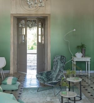A living room with green walls featuring the exquisite chandelier is adorned with Designer's Guild Saraille wallpaper.