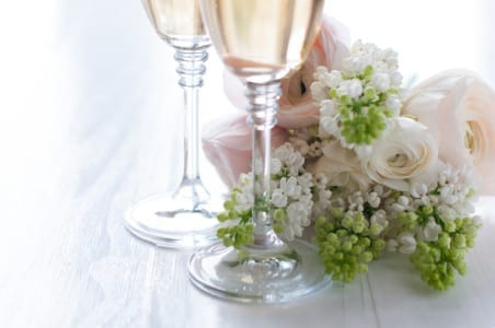 A table adorned with two glasses of champagne and a bouquet of flowers, perfect for newlyweds or as a great practical home gift.