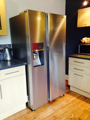 A silver Samsung refrigerator with Food Showcase in a kitchen with wooden floors.