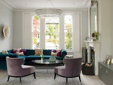 A living room with bold purple couches and a bright fireplace.