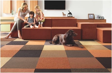 A family is sitting on a couch in their cozy home, surrounded by the stylish commercial flooring of their living room.