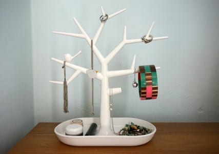 A chic white tree-shaped jewelry holder on a table.