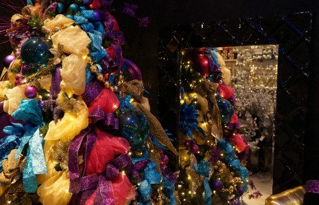 A tree adorned with colorful ribbons, bows, and Christmas lights.