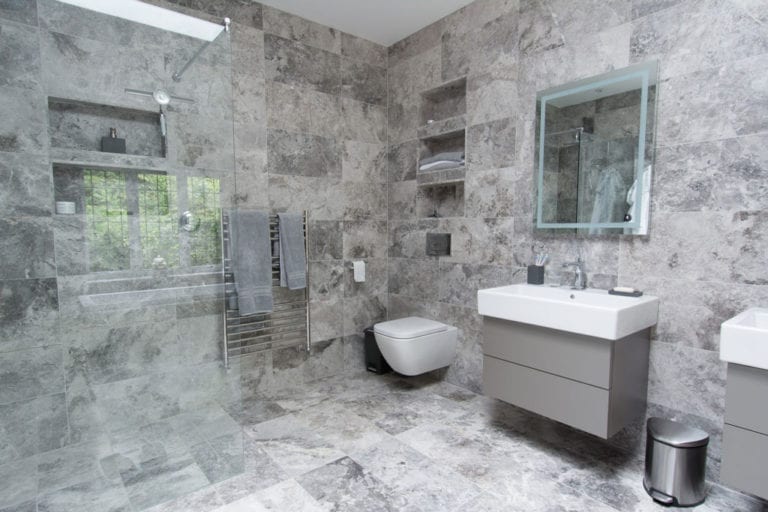 A bathroom with natural stone tiles on the floor.