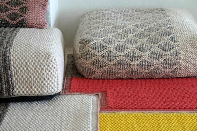 Two Spanish Design Tour knitted poufs on a floor next to each other.