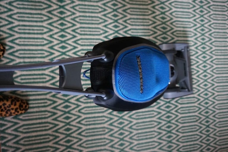 A blue vacuum cleaner making housekeeping better on a green carpet.