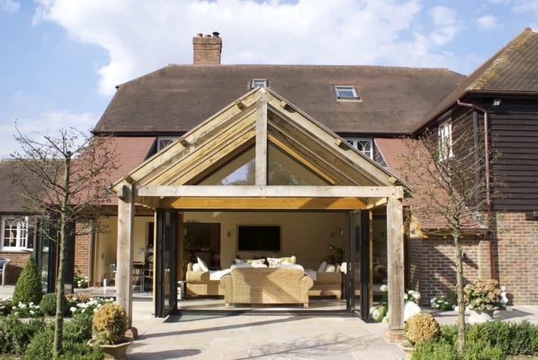 A large house with a spacious patio area featuring aluminium bi-fold doors that offer numerous benefits.