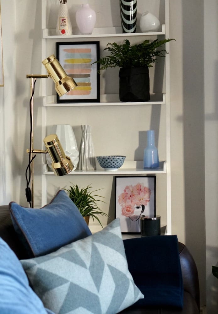 A Happy Home living room makeover with a white shelf and blue pillows from Urbanara.