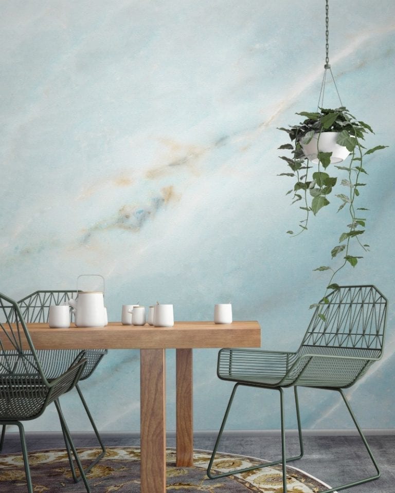 A dining room with a table and chairs against a blue wall featuring marble wallpapers.