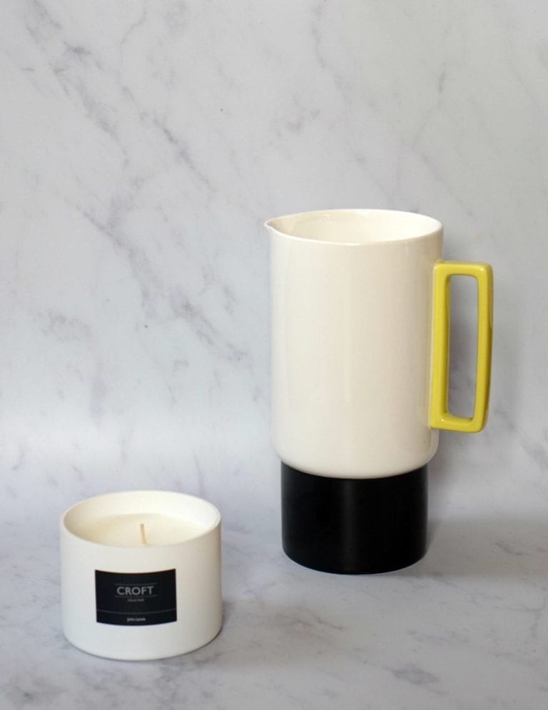A white coffee pot next to a yellow candle, perfect as Mother's Day Gifts for the Home Lover.