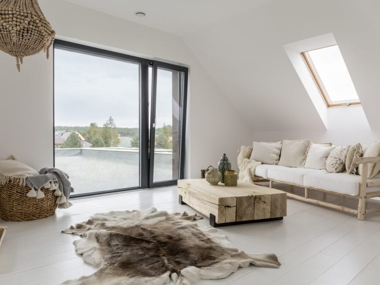An attic living room with white furniture and a cowhide rug, installed with attic roof windows for ample natural light.