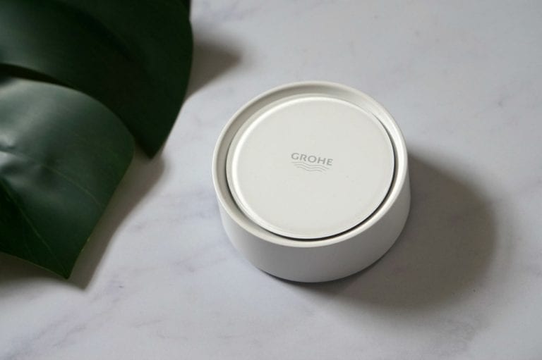 The Grohe Sense Water Detection System, a white device, sitting on top of a marble table in a smart home.