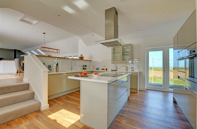 Peacehay Barn, a holiday home in Cornwall, featuring a kitchen with wooden floors and a staircase leading up to it.