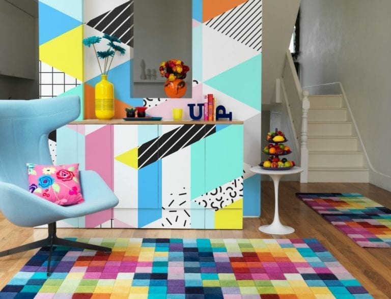 A colorful rug and chair, accompanied by vibrant wall art, create an easy and creative atmosphere in the living room.