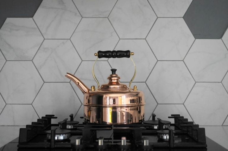 A copper tea kettle sits on top of a stove, making it the perfect gift for a home lover during Christmas.