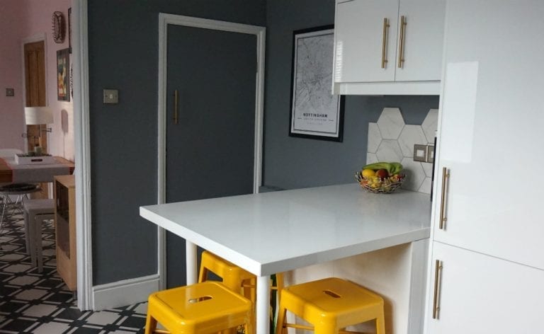 A kitchen with yellow stools and a white maxtop quartz counter top.