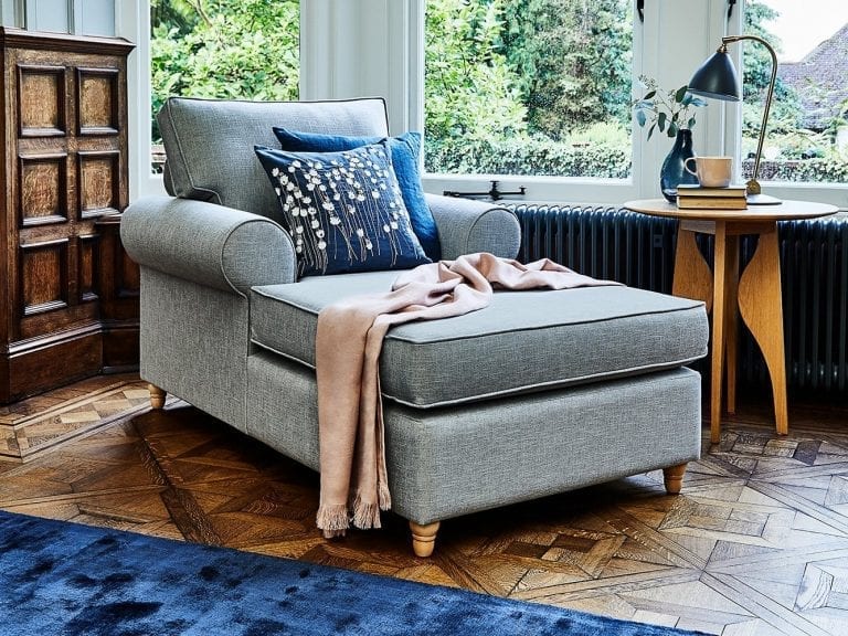 A small living room with a blue rug and a blue chair.