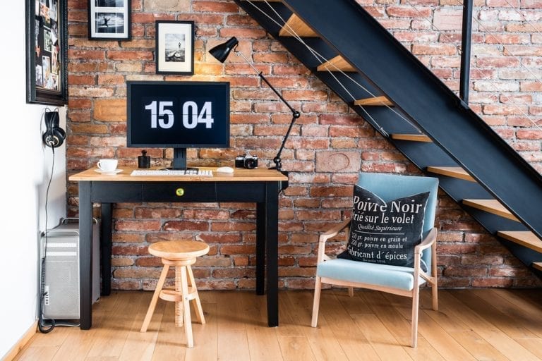 A home office with a desk, chair and stairs made of bricks.