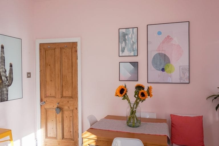 A pink dining room with sunflowers on the table and a gallery wall.