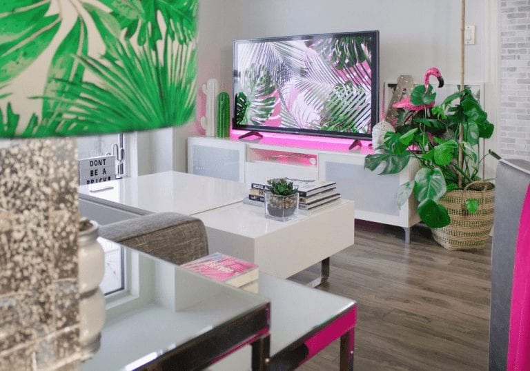 A self storage unit with a living room set up, including a tv and pink and white decor.