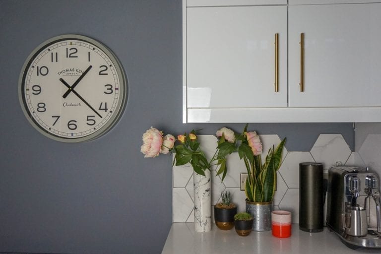 A grey kitchen with a clock on the wall, perfect for home decor.