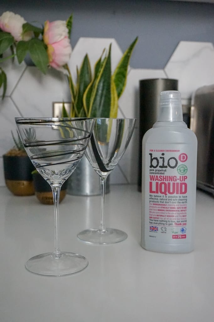 A bottle of bio liquid sits next to a glass of vegan wine.