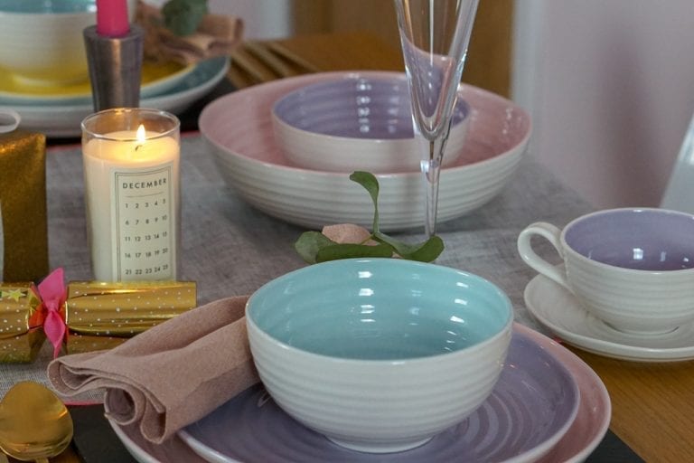 A pastel table setting with pink, purple, and blue plates and cups.