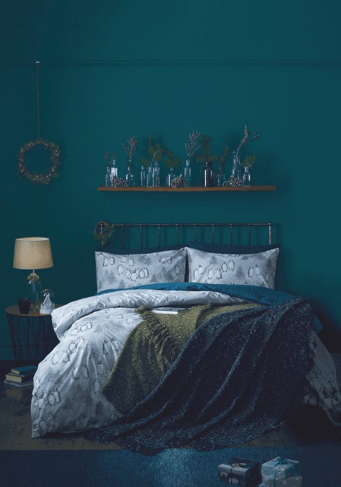 A warm bedroom with teal walls and a bed.