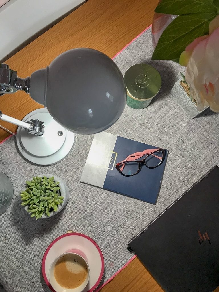 A desk with an Ottlite Wellness Desk Lamp, a laptop and a cup of coffee. Enter our giveaway for a chance to win!