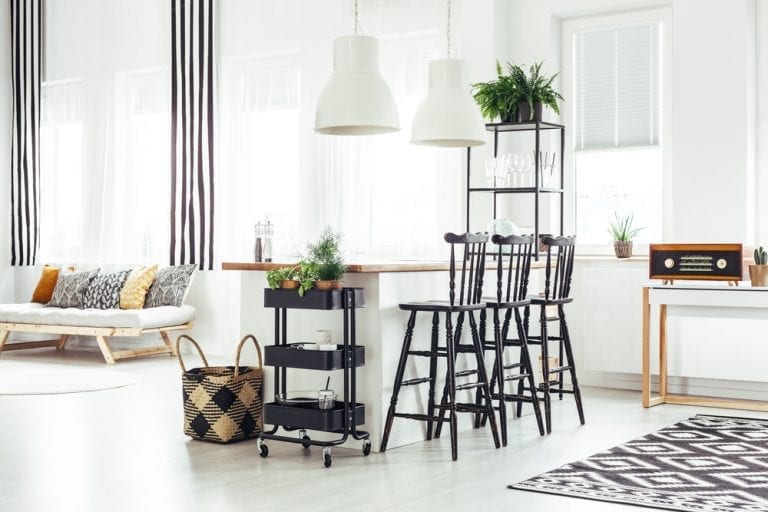 A stylish white and black living room is decorated with a stunning black and white rug.