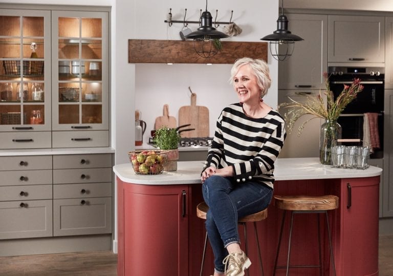 A woman sitting on a stool in a trendy kitchen.