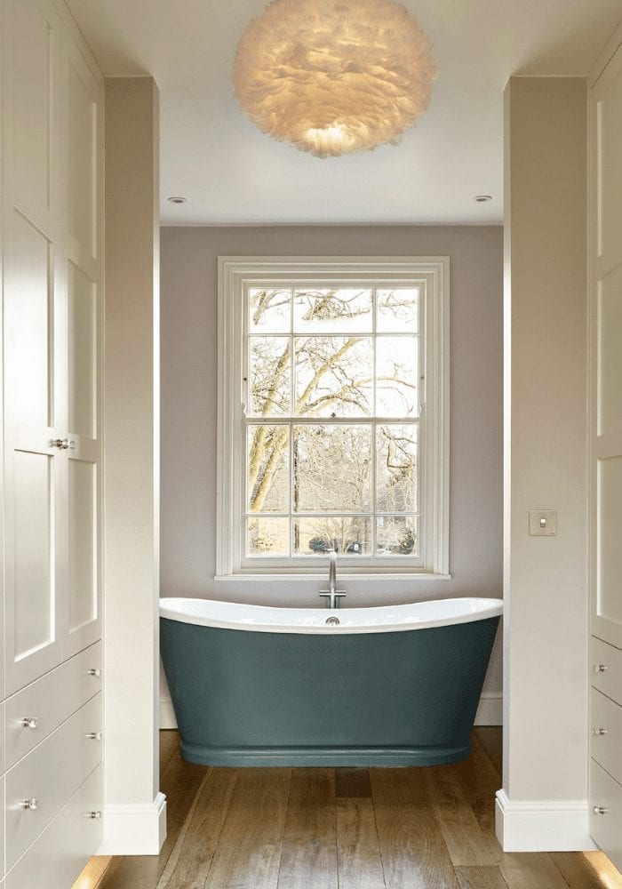 A bathroom with blue bath tub and wooden floors offers a cozy and inviting atmosphere for relaxation.