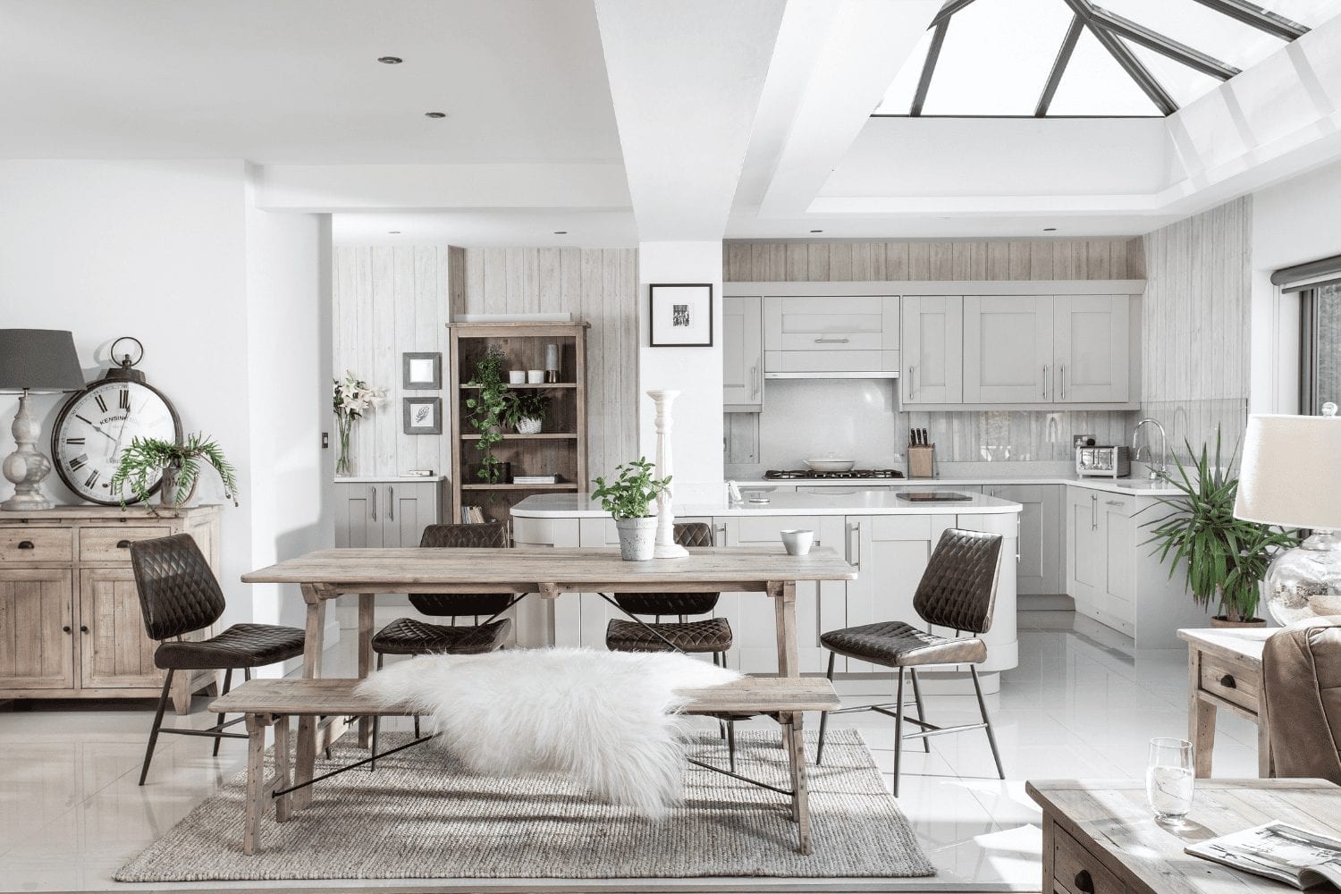 Tips for boosting home decor: A white kitchen and dining room with a skylight.