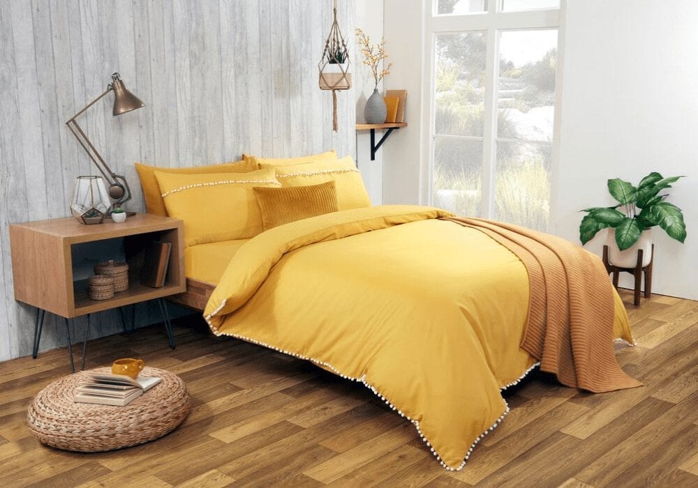 A cozy yellow bedroom with wooden floors and a modern yellow duvet.