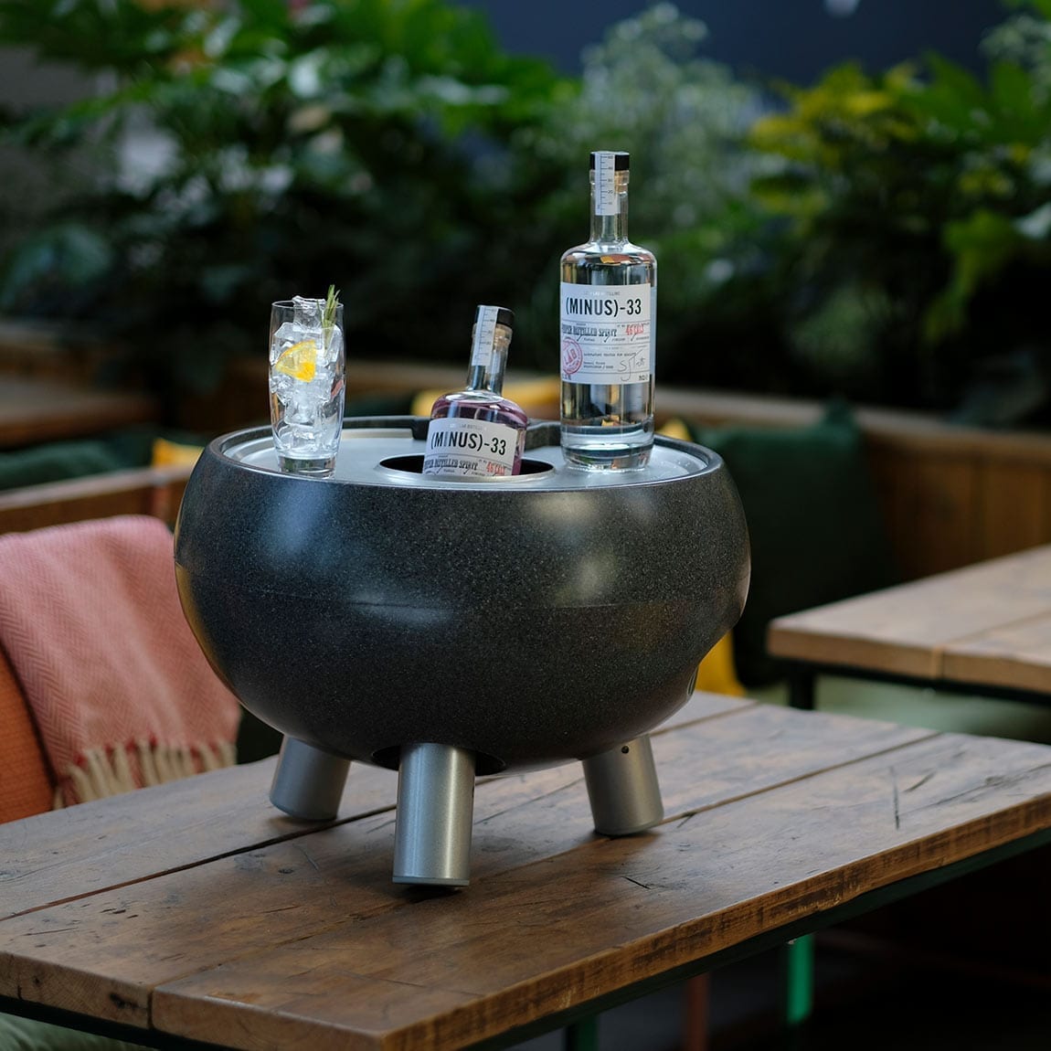 A bottle of liquor is sitting on a wooden table in the garden, creating a relaxing atmosphere.