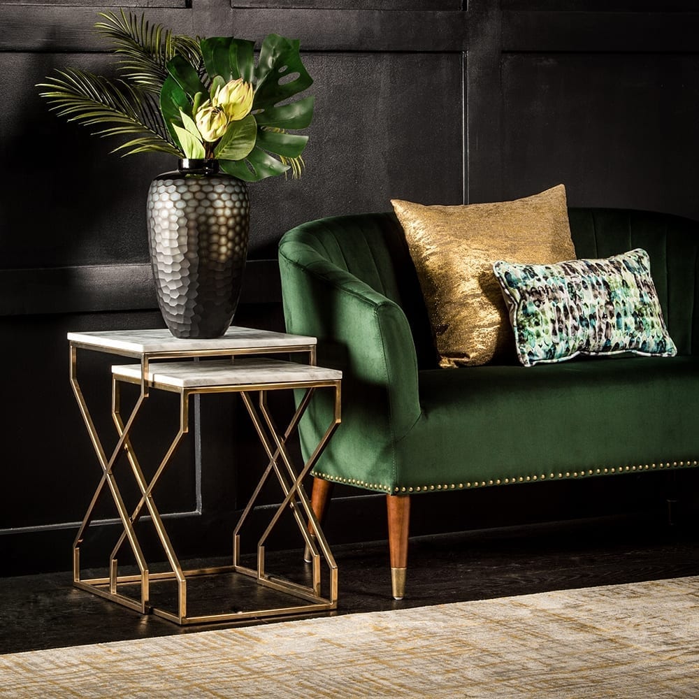 A green velvet sofa with gold accents adds elegance to a small home. It is the perfect key piece to decorate in front of a black wall.