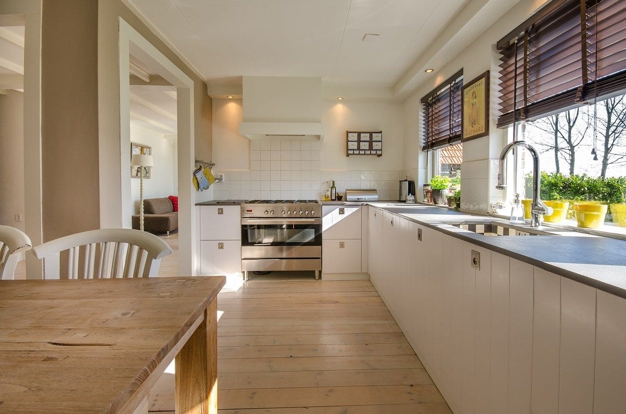 A white kitchen with a wooden table, chairs, and a contemporary look.