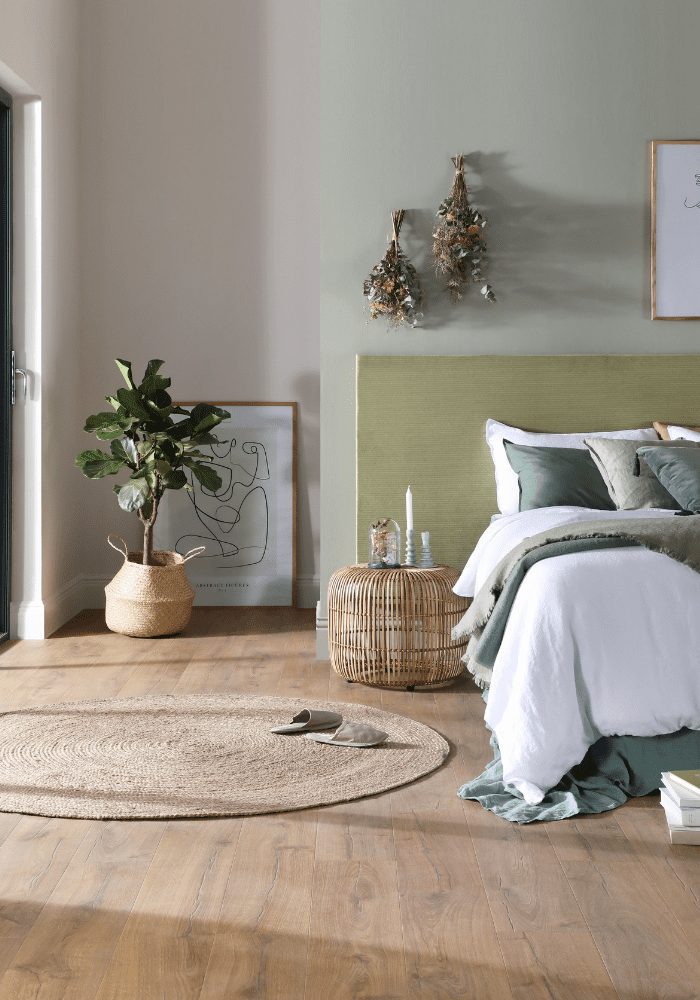 Bedroom with white bedding, green walls, wooden floor and interior design trends 2022