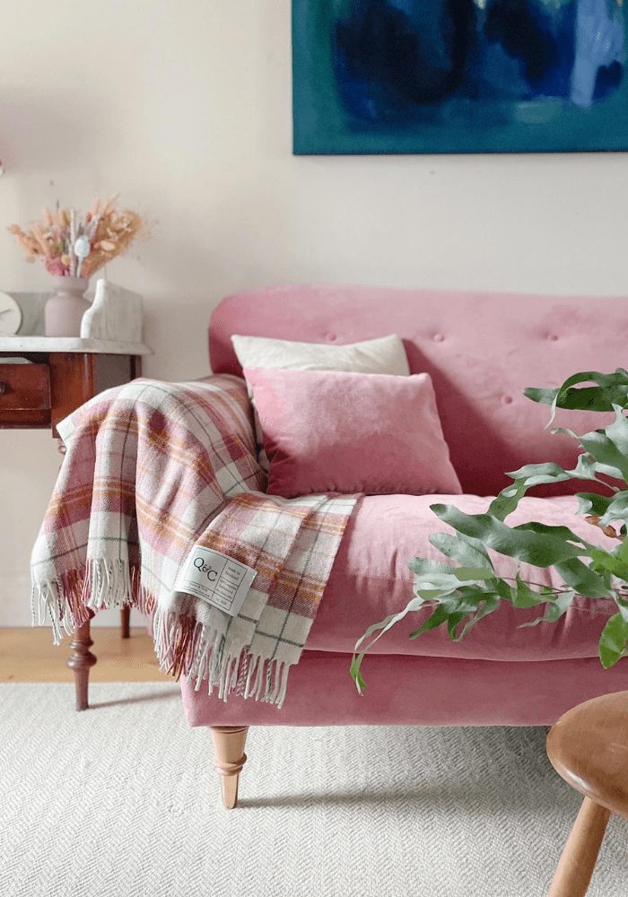 pink sofa with a pink check tartan throw (a fabric trend) in a cream room