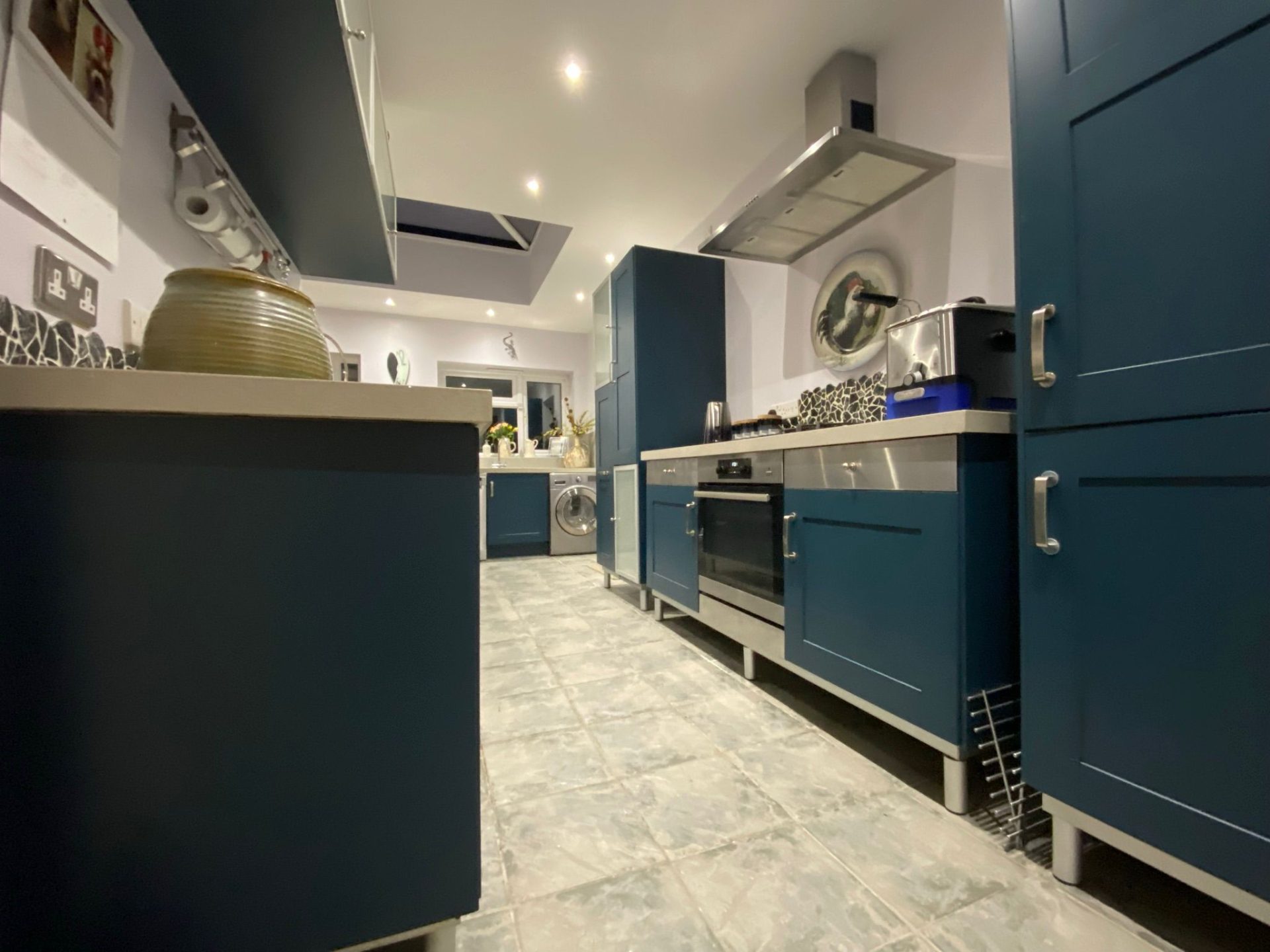 Modern kitchen interior with blue cabinets and kitchen spraying, featuring stainless steel appliances.