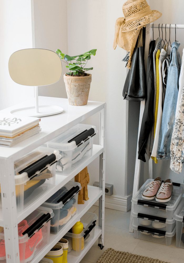 plastic clothes storage boxes on shelves with a hanging rail