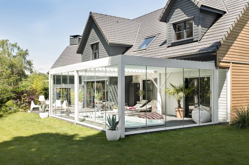 A modern house with a glass conservatory extension to expand your home and a well-maintained lawn.