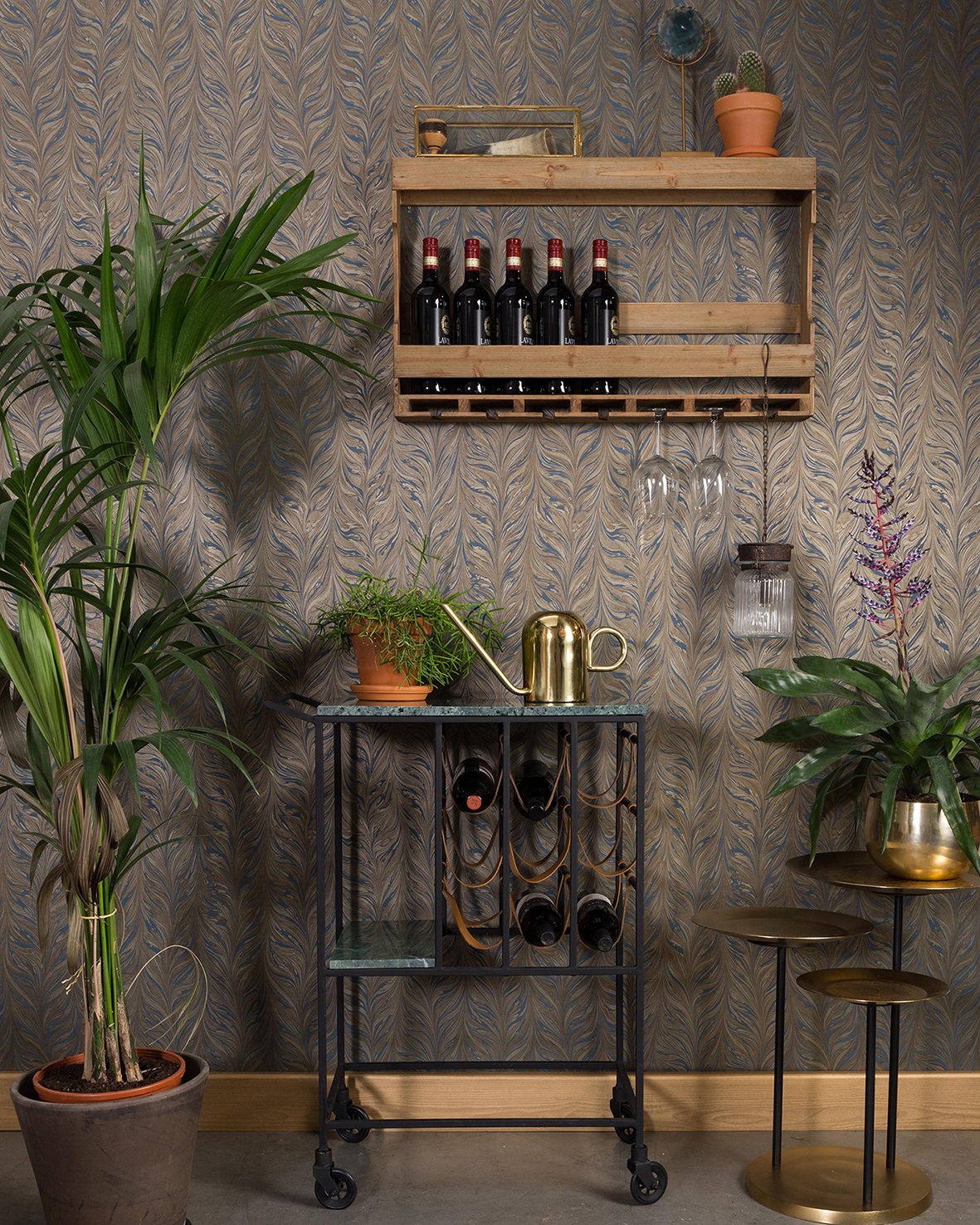 A stylish home wine storage area with a plant theme, featuring a bar cart, wine shelf, and decorative greenery.