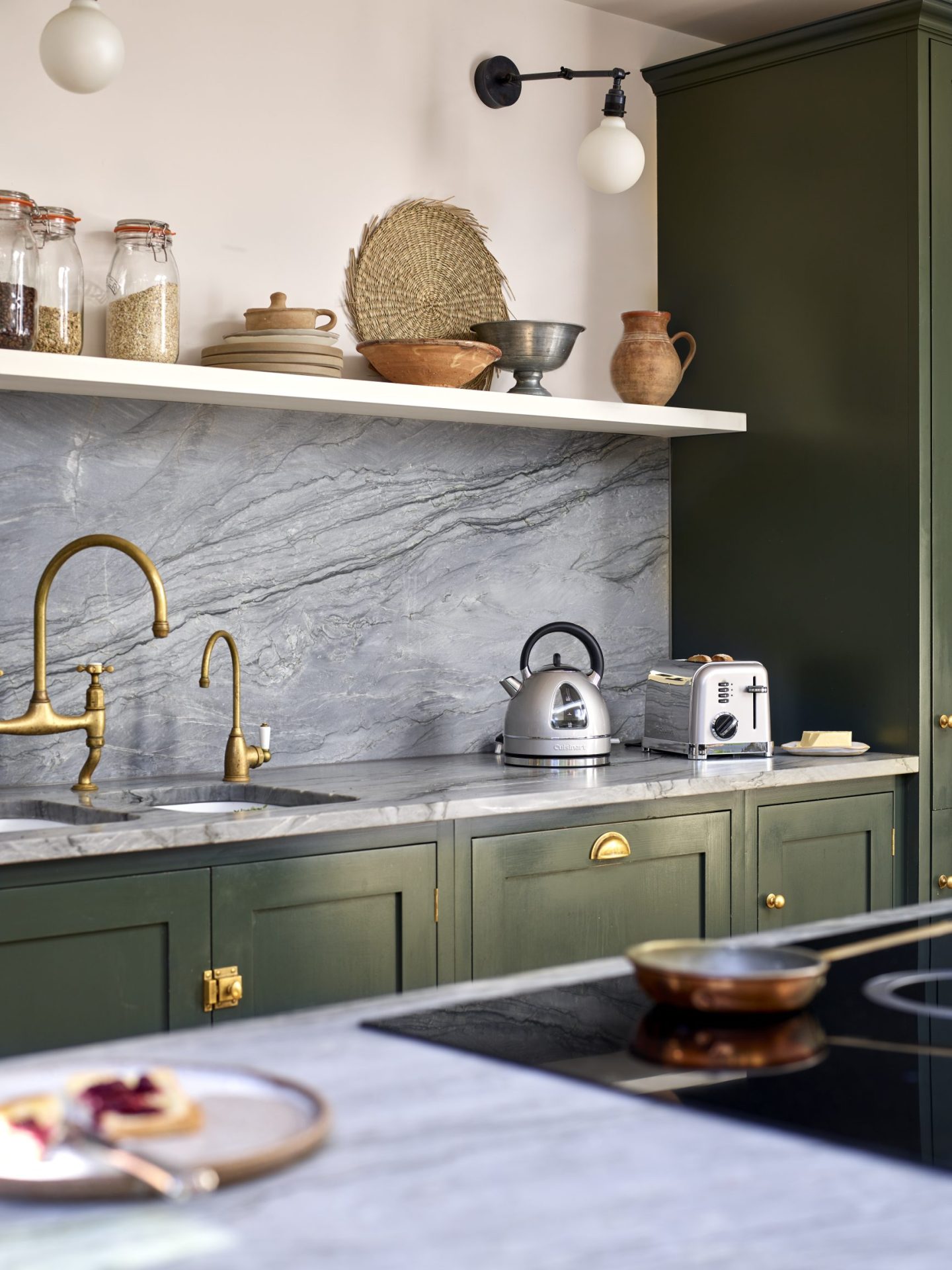 marble glass splashback in a green ktichen with white walls and high shelf